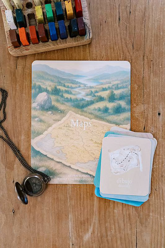 Cards on a table with a compass necklace and crayons.