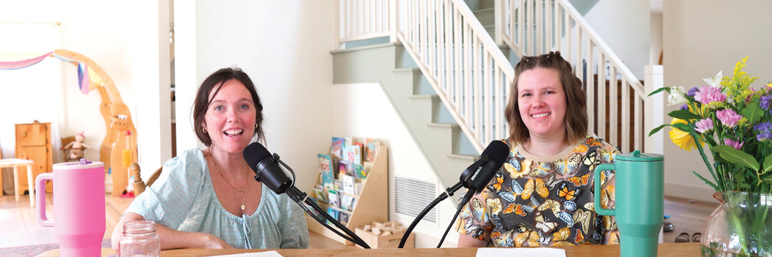 two women sitting at a table with microphones