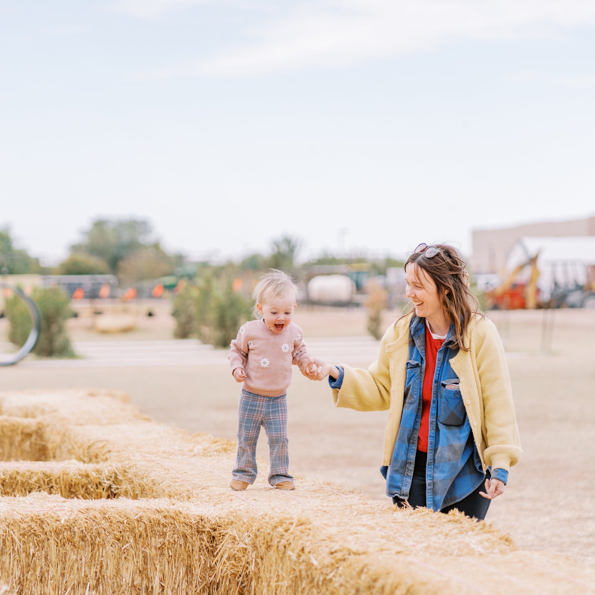 Woman and child standing on a field of hay bales