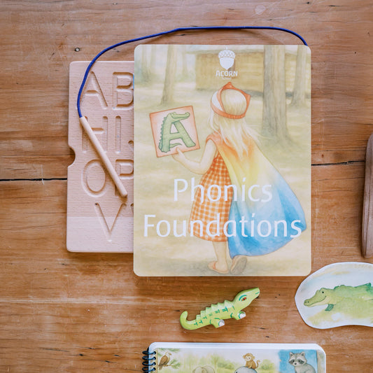 Book titled 'Phonics Foundations' on a wooden surface with educational materials.