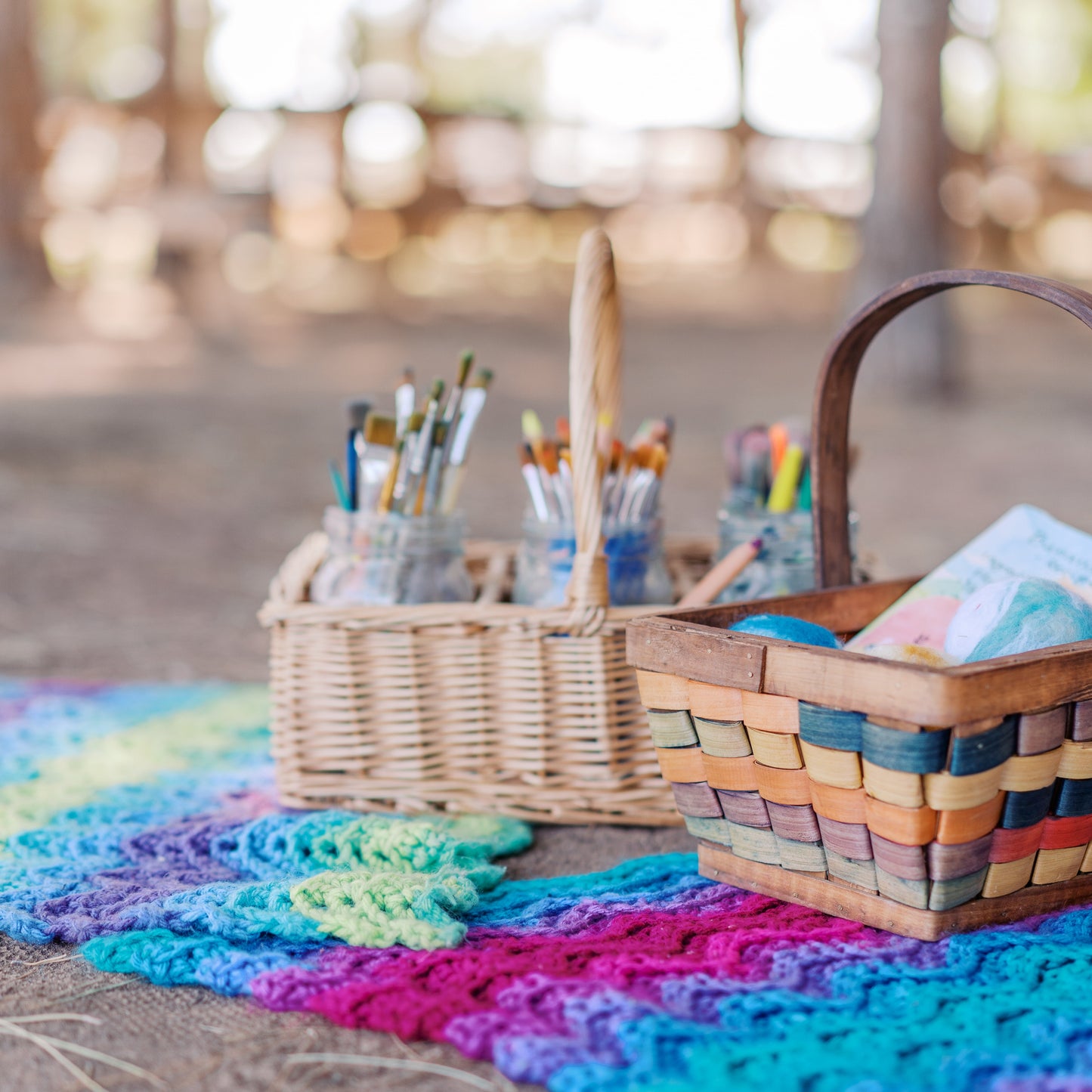 Colorful crocheted blanket with baskets on a wooden surface outdoors.