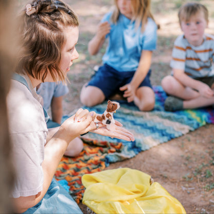 Woman and children sitting on a blanket outdoors with a yellow blanket and basket.