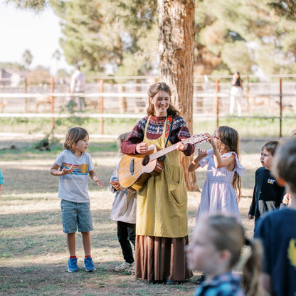Woman playing guitar with children in a park setting