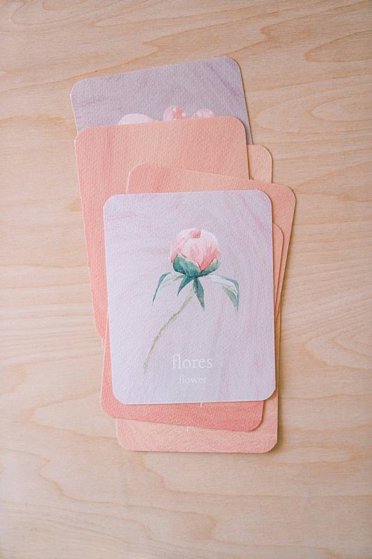 Stack of cards on a table with one card showing a flower illustration