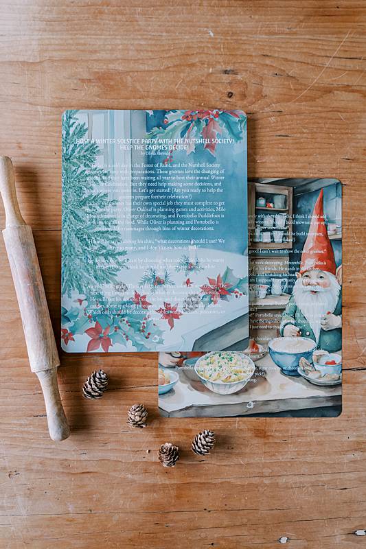 Two cards with pincecones and a wooden roller on a table
