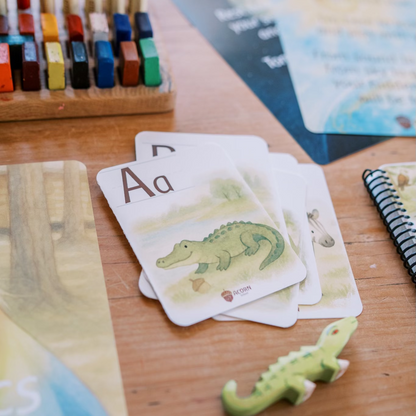 Educational materials including cards with letters and pictures of animals on a wooden surface.