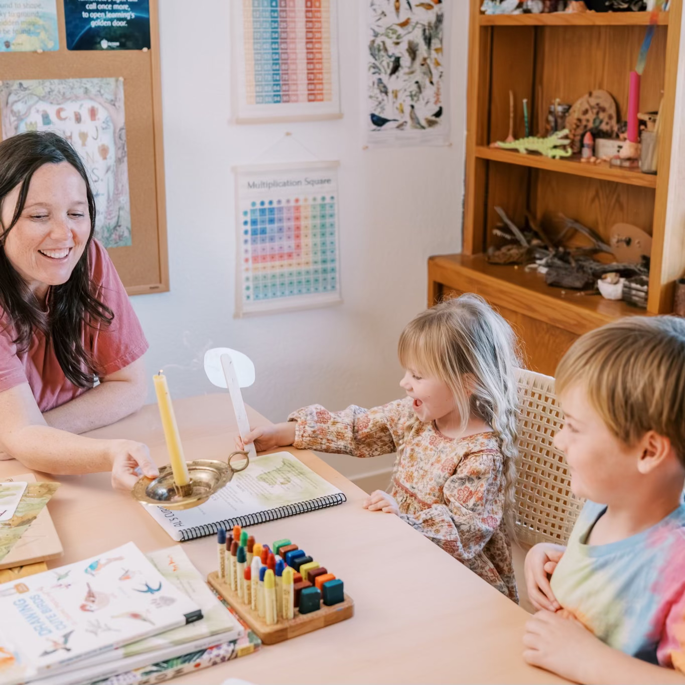 Teacher and students in a classroom setting with educational materials.